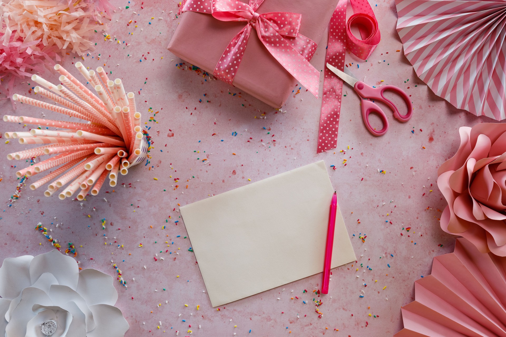 Gift card and birthday party accessories on pink background