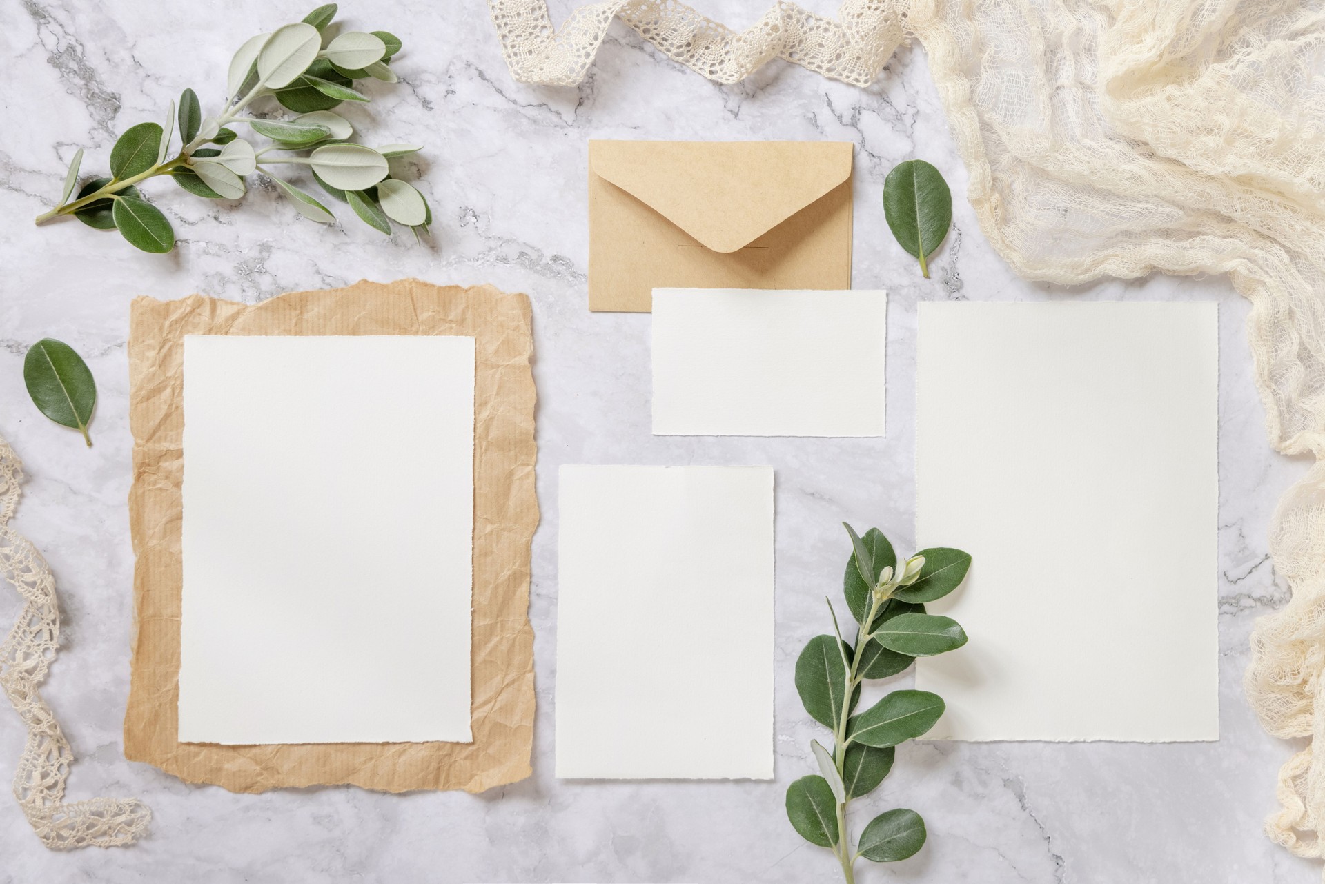 Wedding blank cards laying on a marble table decorated with eucalyptus branches